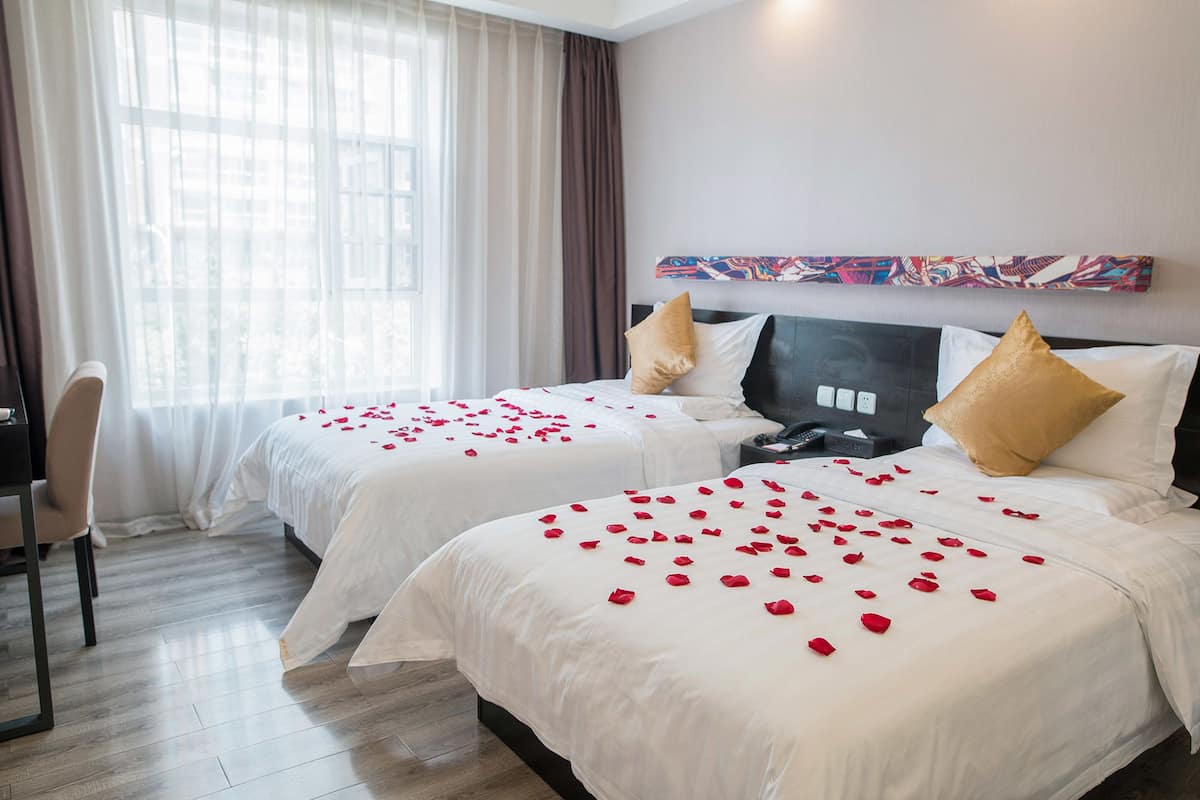 A hotel room with two beds, a desk, and a chair.