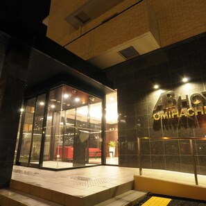 A hotel entrance with a glass door, a visible seating area inside, and a sign with partially visible text. - Ab Hotel Omihachiman (Omihachiman)