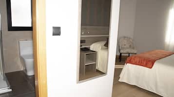Een hotelkamer met een bed, een bureau met stoel, een douche en een toilet.