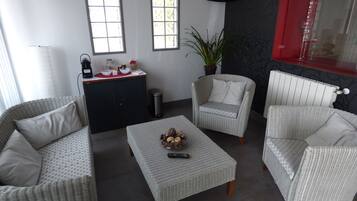 A modern living room with wicker furniture, a coffee table, a cabinet, and a potted plant.