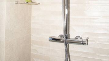 A modern shower with a square head, a handheld showerhead, and a handheld faucet.