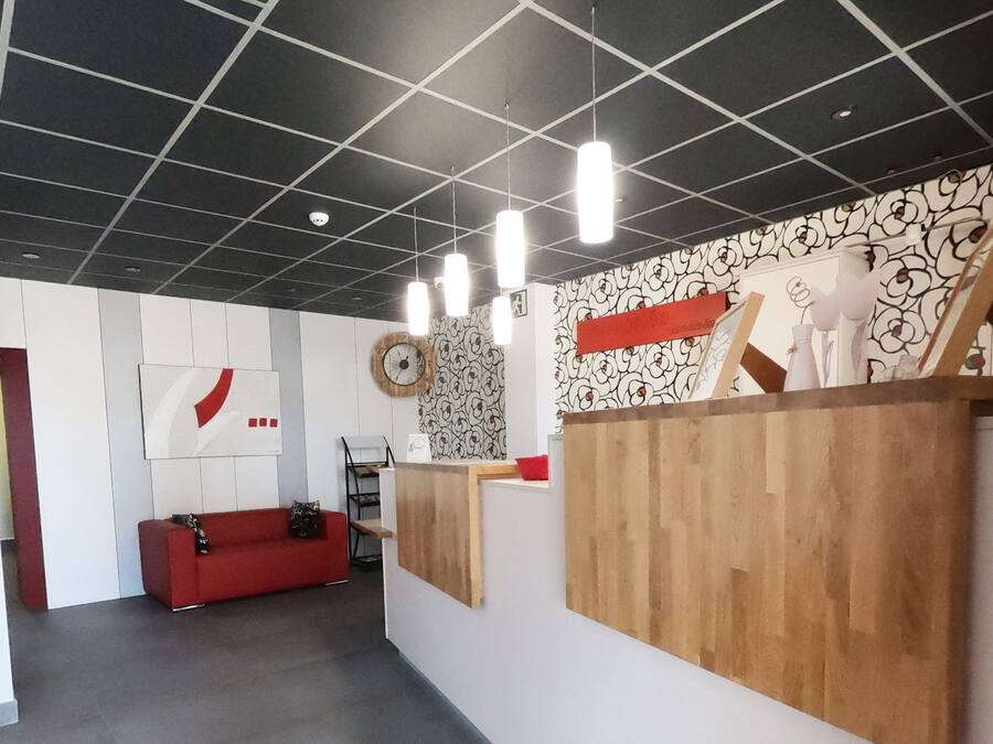 A modern interior with a reception desk, a red sofa, and a patterned wall.
