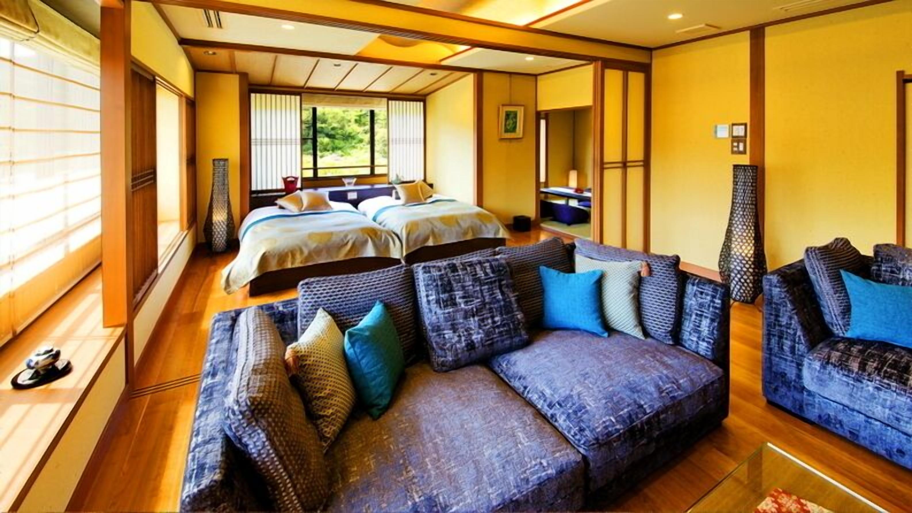 A hotel room with two beds, a sofa, and a dining area.