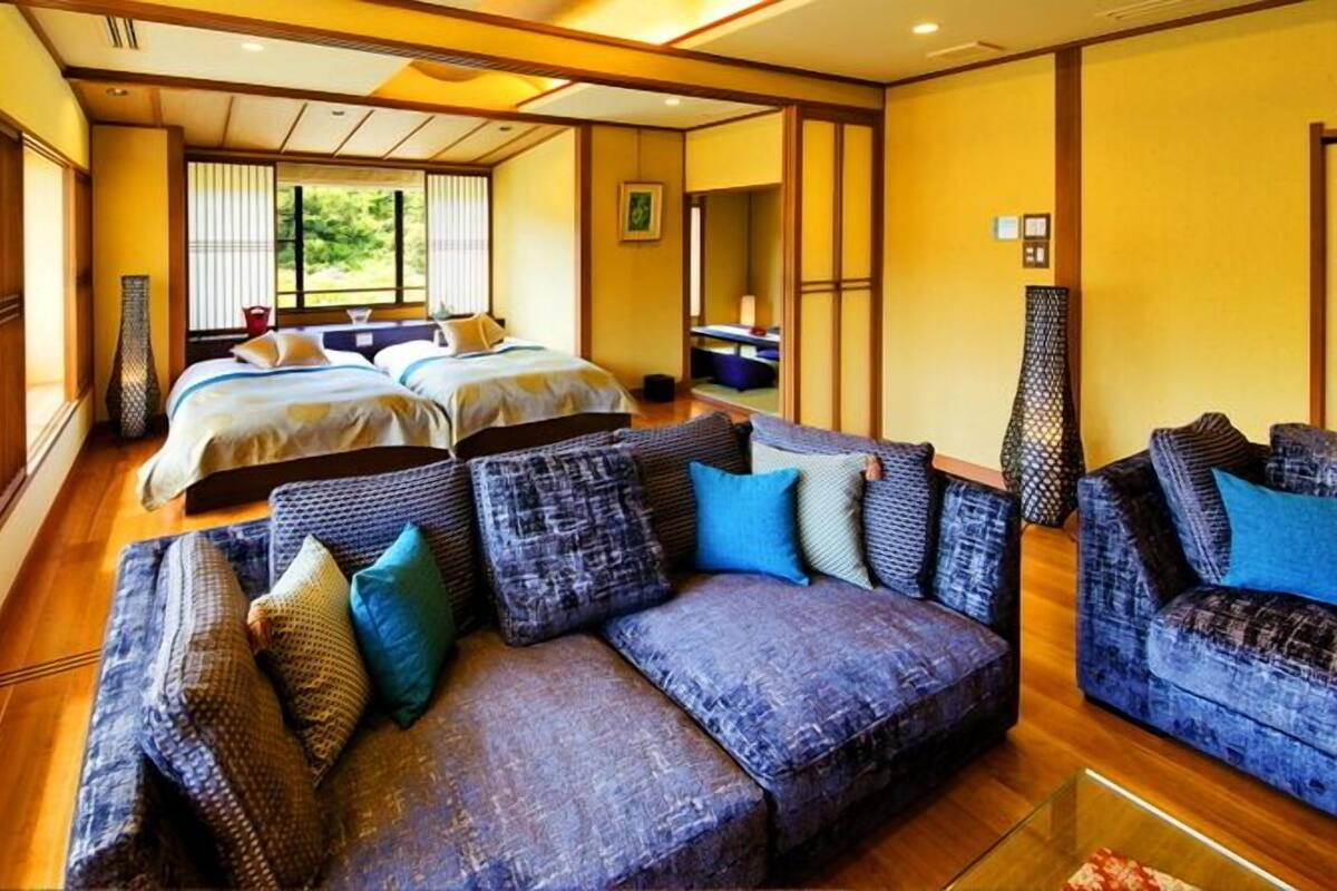 A hotel room with two beds, a sofa, and a dining area.