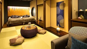 A traditional Japanese-style room with tatami flooring, a low wooden table, and two beds with dark bedding. - Kanazawa Yuwaku Onsen Hyakurakuso (Kanazawa)