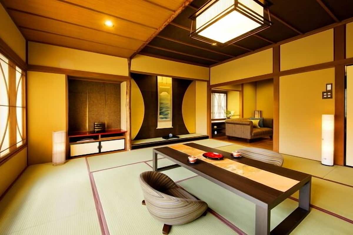 A traditional Japanese-style room with tatami flooring, a low table, a cushioned seating area, and sliding doors.