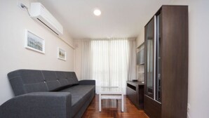 A modern living room with a grey sofa, a white coffee table, and a wooden cabinet. - Obispo Oro Flat ZX3 (Córdoba)