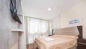 A hotel room with a bed, a flat-screen TV mounted on the wall, a painting on the wall, and a window with curtains. - Obispo Oro Flat ZX3 (Córdoba)