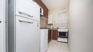 A compact kitchen with a refrigerator, washing machine, microwave, stove, and cabinets. - Obispo Oro Flat ZX3 (Córdoba)