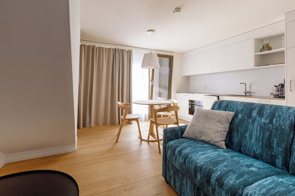 Una sala de estar moderna con un sofá color turquesa, una mesita redonda y sillas.