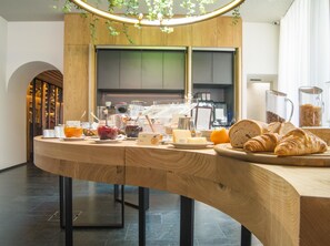 A breakfast buffet with various food items and a wooden counter.