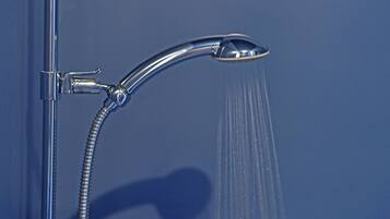 A chrome shower head with water flowing from it.