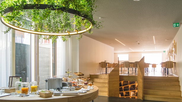 A modern cafe with a wooden counter, a coffee machine, and a variety of breakfast items. - Albergo Croce Bianca (Poschiavo)