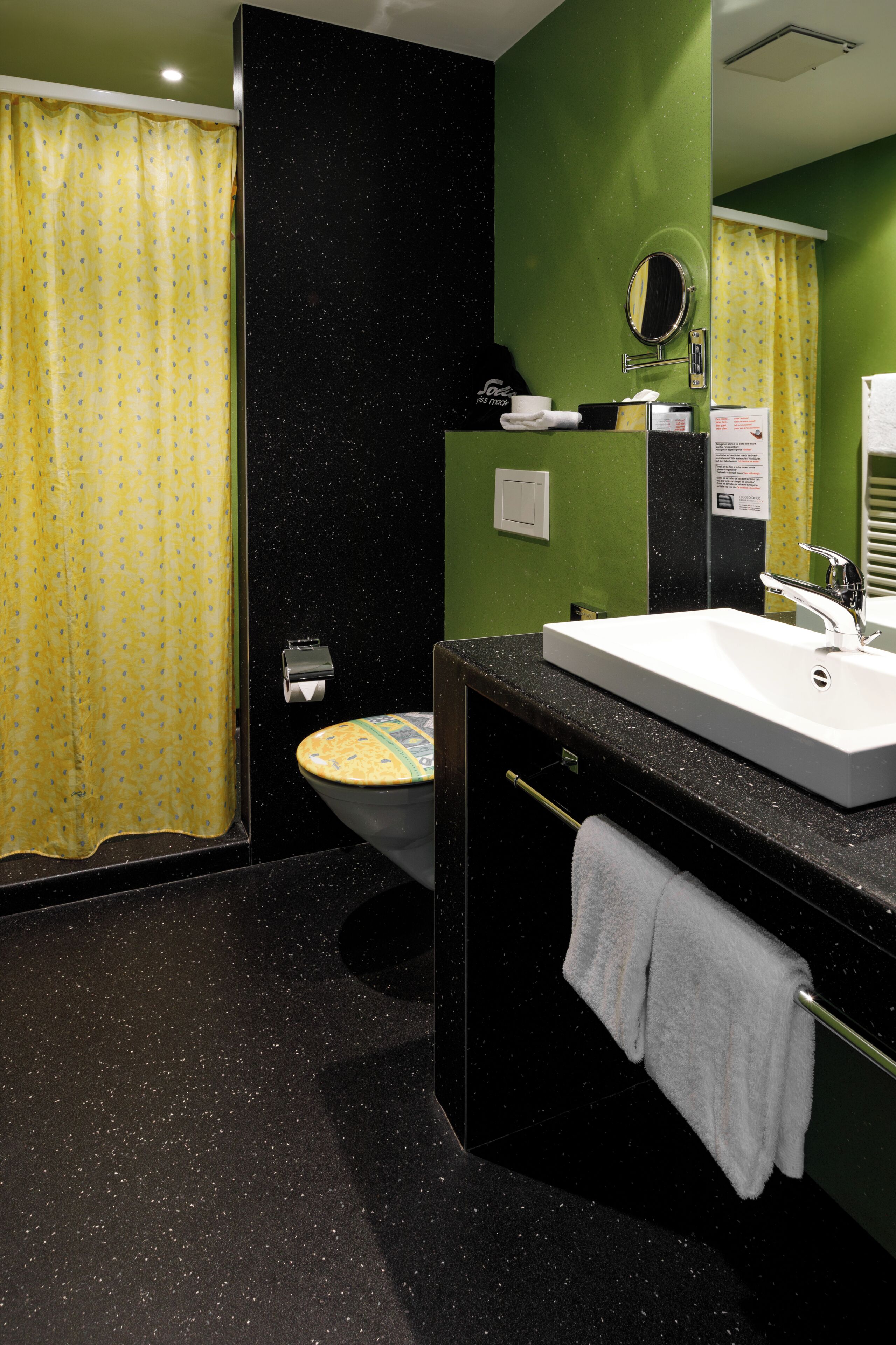 A bathroom with a toilet, sink, mirror, and towel rack.