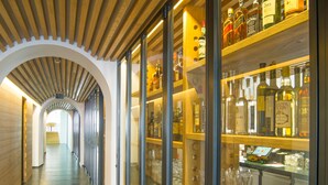 A corridor with wooden paneling and glass display cases filled with bottles and glasses. - Albergo Croce Bianca (Poschiavo)