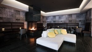 A modern hotel room with a large bed, a fireplace, and a seating area with chairs and tables. - Albergo Croce Bianca (Poschiavo)