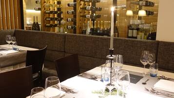Une table dressée pour deux personnes dans un restaurant, avec des verres à vin, des couverts et un menu.
