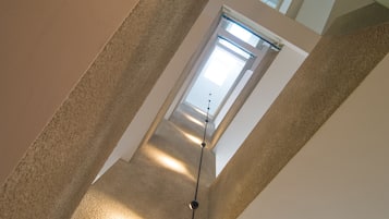 A staircase with a modern design, leading to a bright room with a large window.