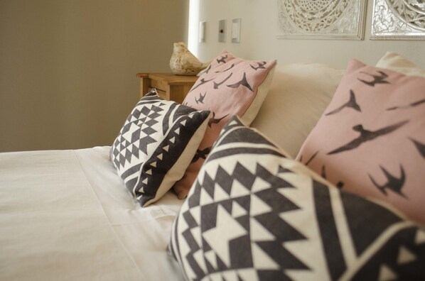 Una cama con almohadas estampadas y un adorno de pared decorativo.