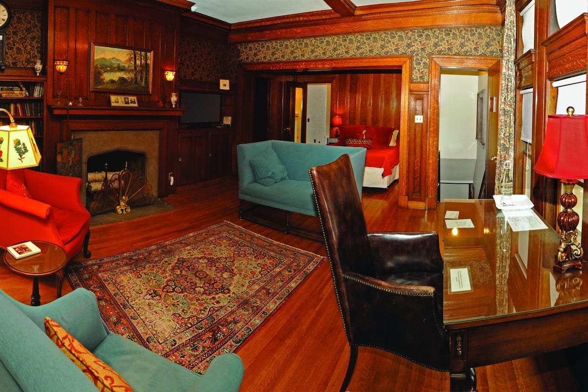 A traditional room with a fireplace, a dining table, and two sofas.