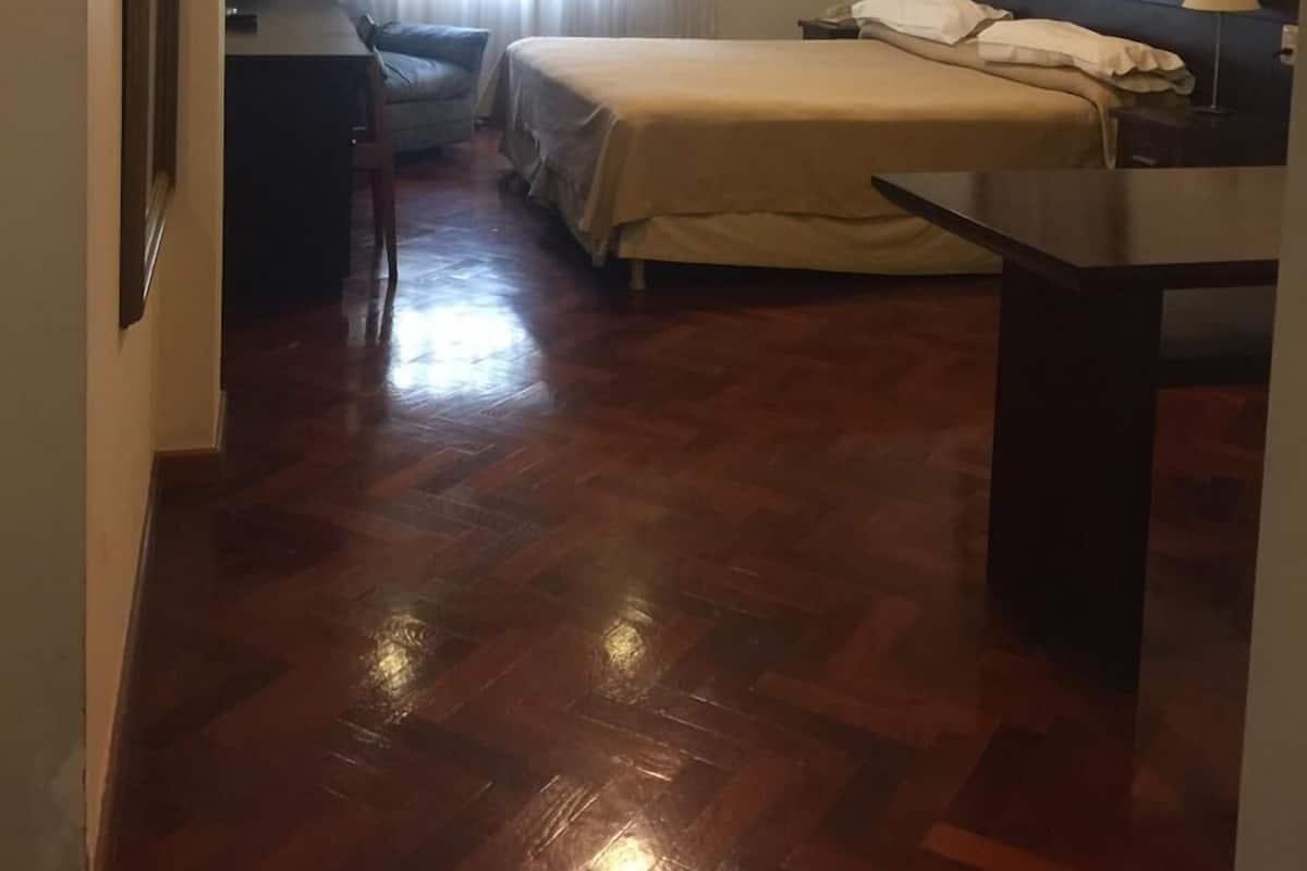 A hotel room with a bed, a desk, a chair, and a window with curtains.