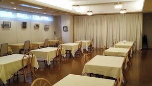 Un comedor con varias mesas y sillas, dispuestas en filas.