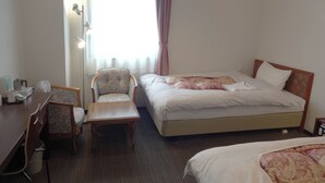 Una habitación de hotel con una cama, un escritorio, una silla y una mesita.