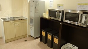 A kitchenette with a refrigerator, microwave, sink, and cabinets. - Hamakita Plaza Hotel (Hamamatsu)