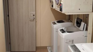 Un cuarto de lavandería con dos lavadoras de carga frontal y una secadora.