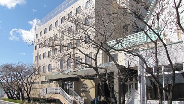 Un edificio de varios pisos con una entrada destacada, una escalera y un amplio frente de cristal.