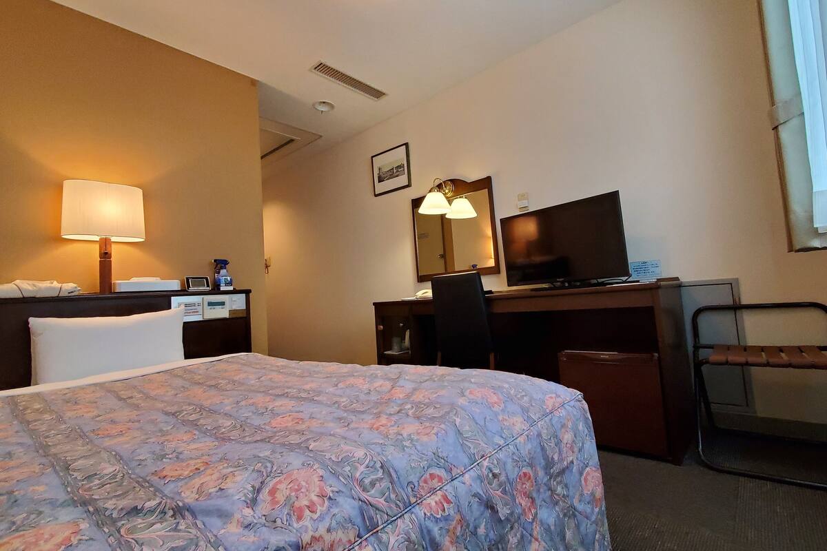 Une chambre d’hôtel équipée d’un lit, d’un bureau, d’une chaise et d’un téléviseur.