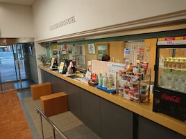A hotel reception area with a counter, various amenities, and a Coca-Cola refrigerator.