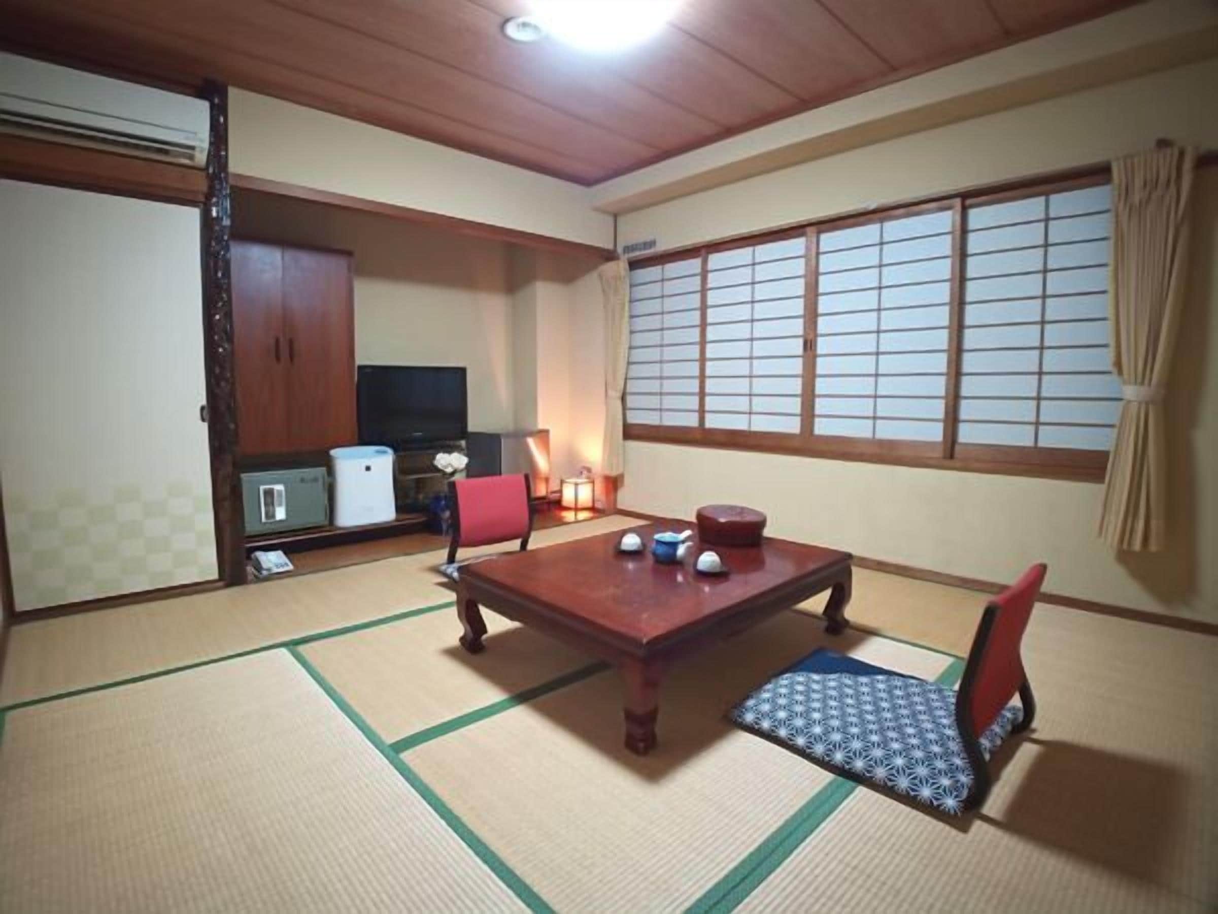 Una habitación japonesa tradicional con suelo de tatami, una mesa baja y un televisor.