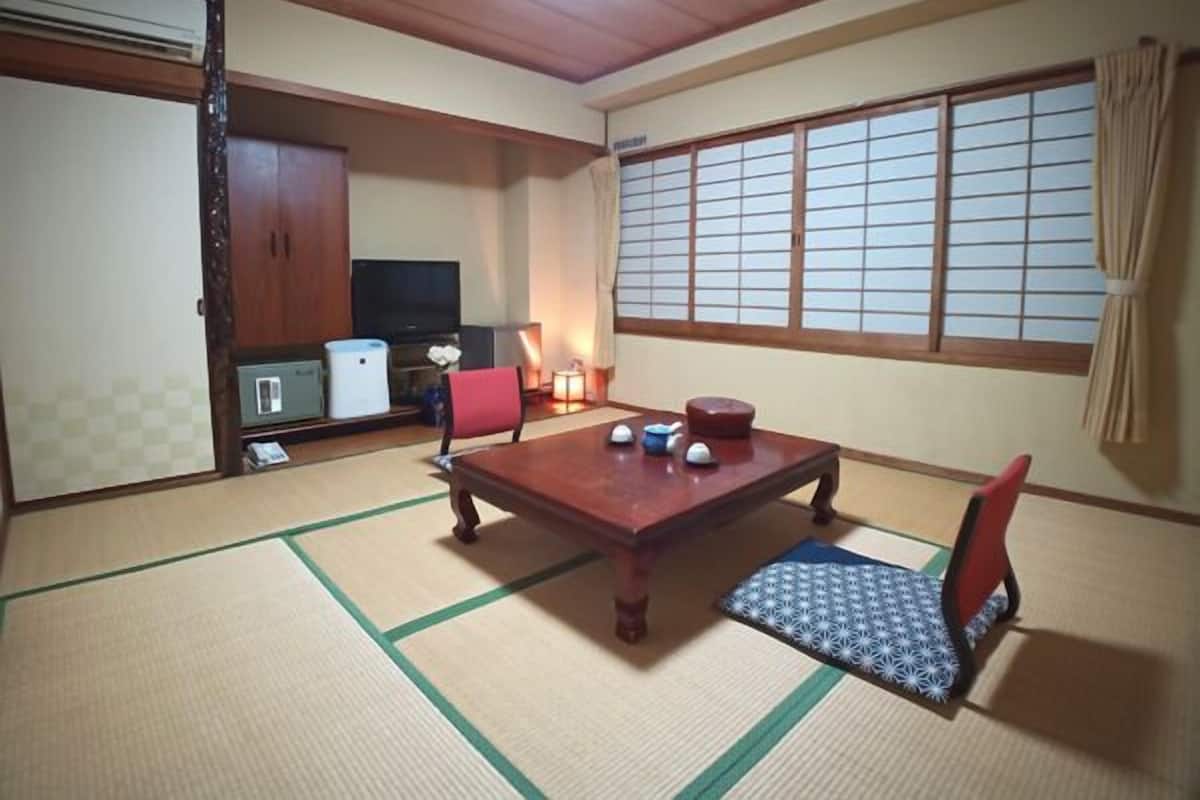 A traditional Japanese room with tatami flooring, a low table, and a television.