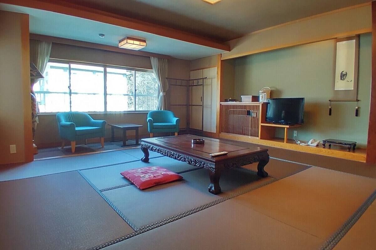 Ein traditioneller japanischer Raum mit Tatami-Bodenbelag, einem niedrigen Tisch und zwei Stühlen.