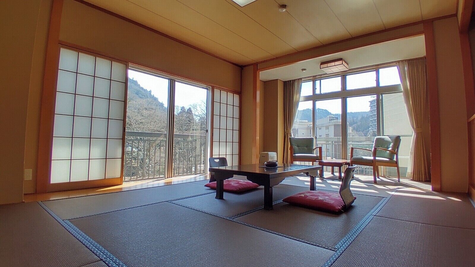 Una habitación con esteras de tatami, puertas correderas, una mesa baja y sillas.