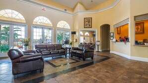 A spacious lobby with leather sofas, a reception desk, and large windows allowing natural light.