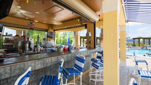 A bar area with a counter, bar stools, and a poolside view.