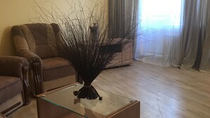 A living room with a glass coffee table, two sofas, a decorative vase, and a large window with curtains. - Appartments in the city center (Kyiv)