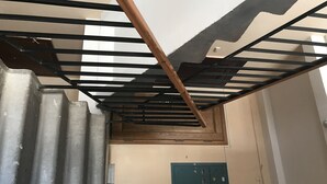 A room with a metal-framed ceiling, a wooden beam, a green utility box, and a corrugated metal wall. - Appartments in the city center (Kyiv)