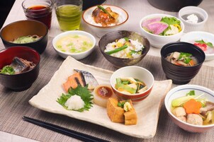 Különféle japán ételek, szépen elrendezve egy asztalon, pálcikákkal és kis tálakkal.
