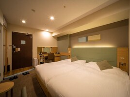 A hotel room with a bed, desk, chair, and a small table.
