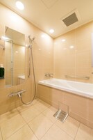 A modern bathroom with a bathtub, shower, and a hand dryer.