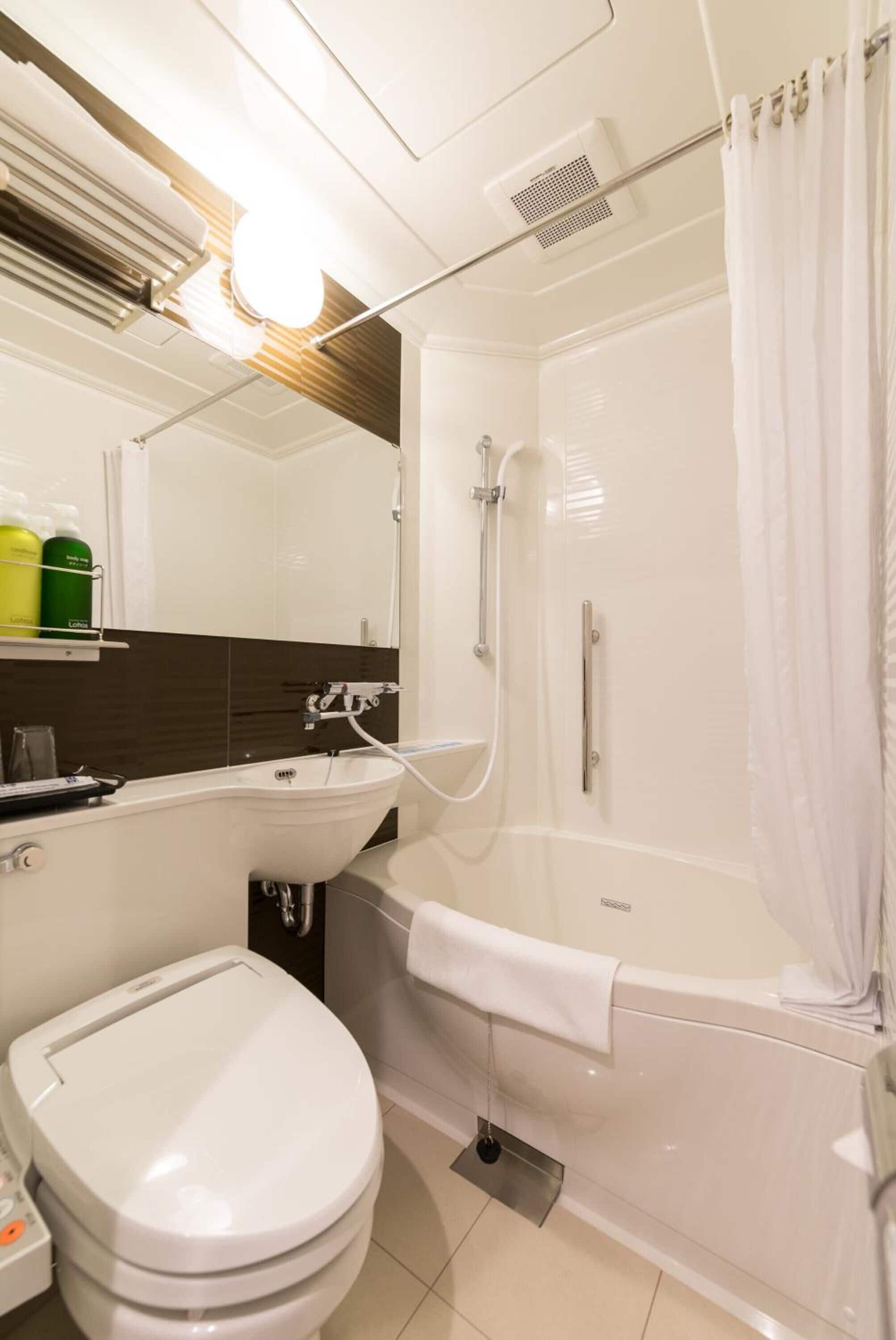 A bathroom with a toilet, sink, and shower area.