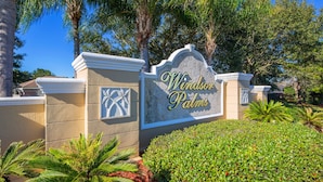 Schild für 'Windor Palms' mit Palmen-Design, umgeben von üppiger Vegetation.