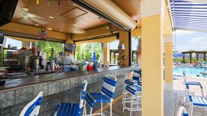 Een bar met uitzicht op het zwembad, inclusief een bar, zitplaatsen en ligbedden bij het zwembad.