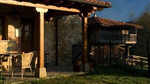 Un edificio de piedra con un patio cubierto, mobiliario exterior y una terraza de madera.