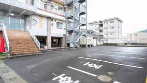 Un hotel con un edificio de varios pisos, un área de estacionamiento y una escalera que conduce a la entrada.