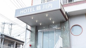Entrada de hotel con un letrero, una escalera y una puerta de cristal.