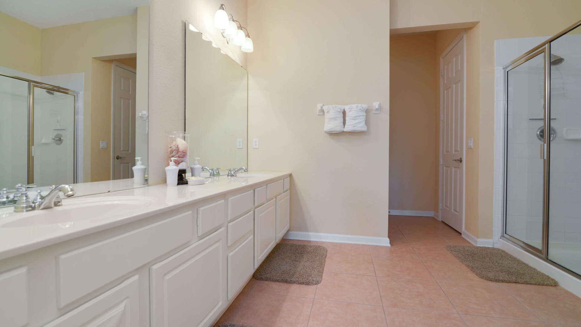 A bathroom with a large mirror, a double sink, and a glass shower enclosure.